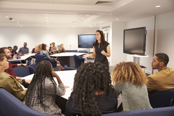 Woman speaking in front of adults - Teach Plus