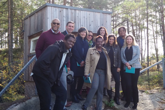 Smiling group, ten people, posing for photo on a trail in sunlight forest