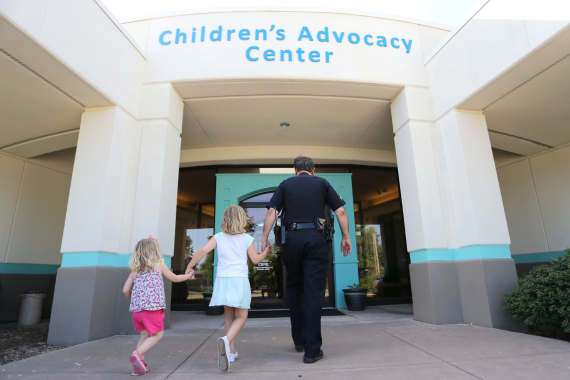 Protecting Vulnerable Children, policeman walking two children into Children's Advocacy Center