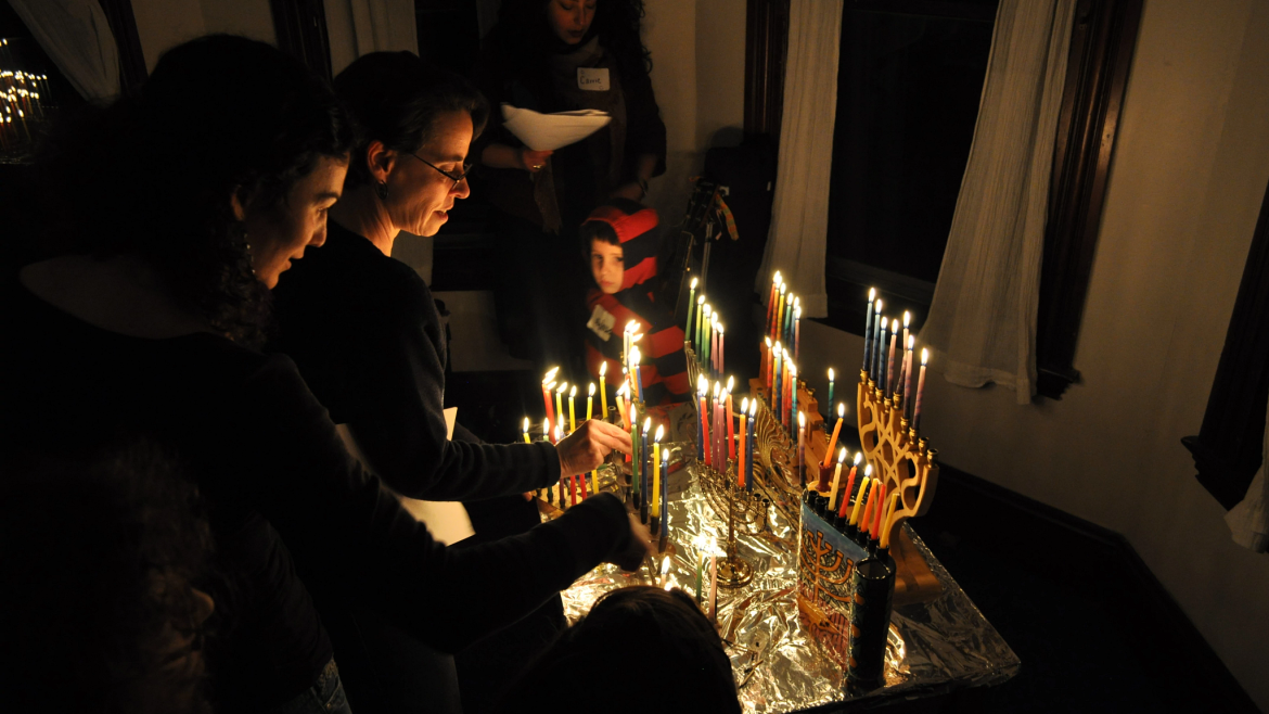 Two people lighting menorahs