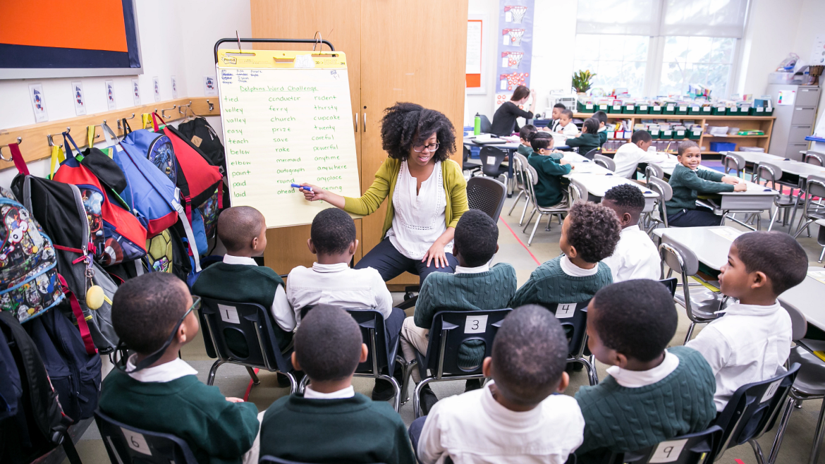 Smiling teacher, class of young boys listening