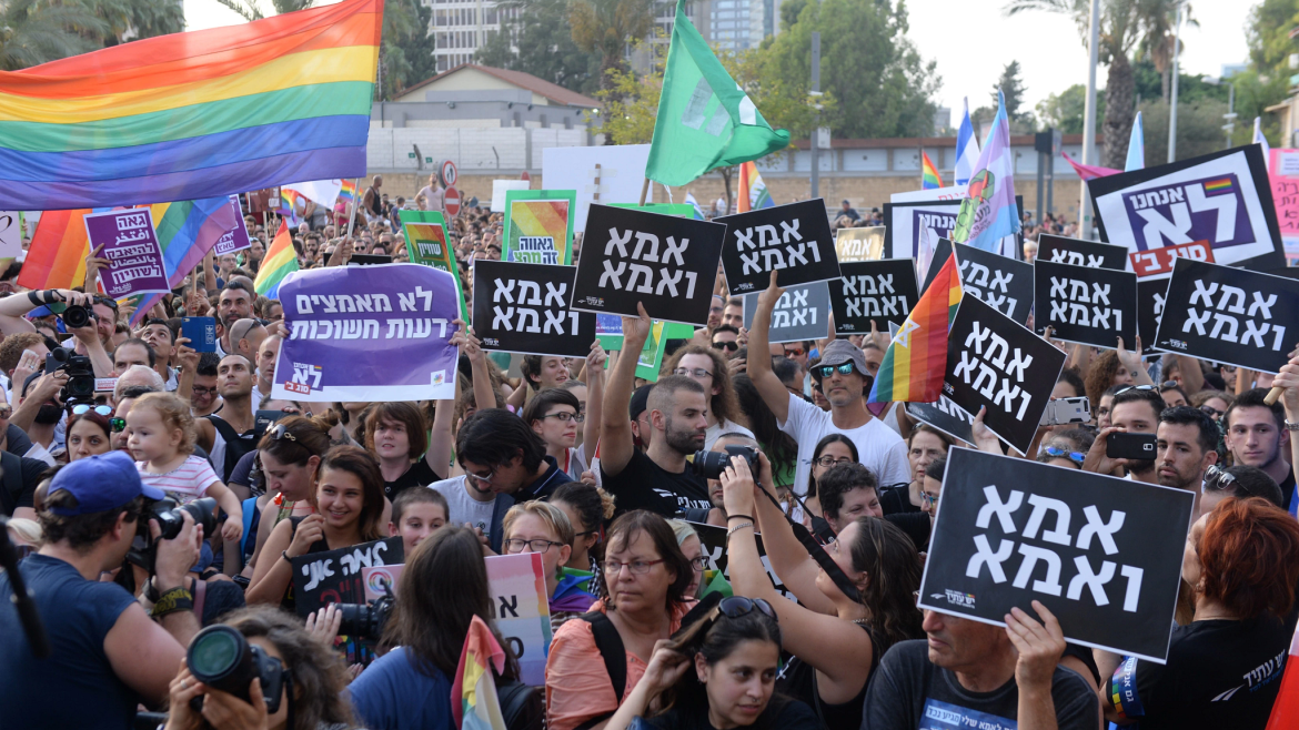 Rainbow banner, crowd with Hebrew signs, LGBTQ demonstratin in Israel