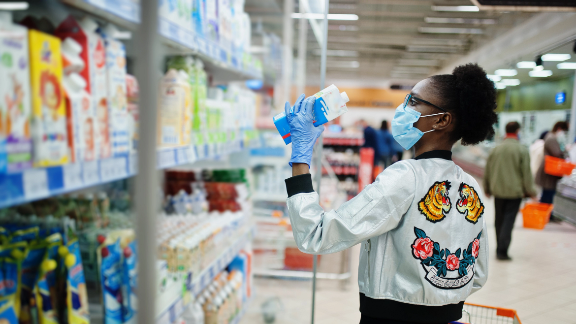 Woman wearing mask and gloves looking at cleaning supplies on a store shelf
