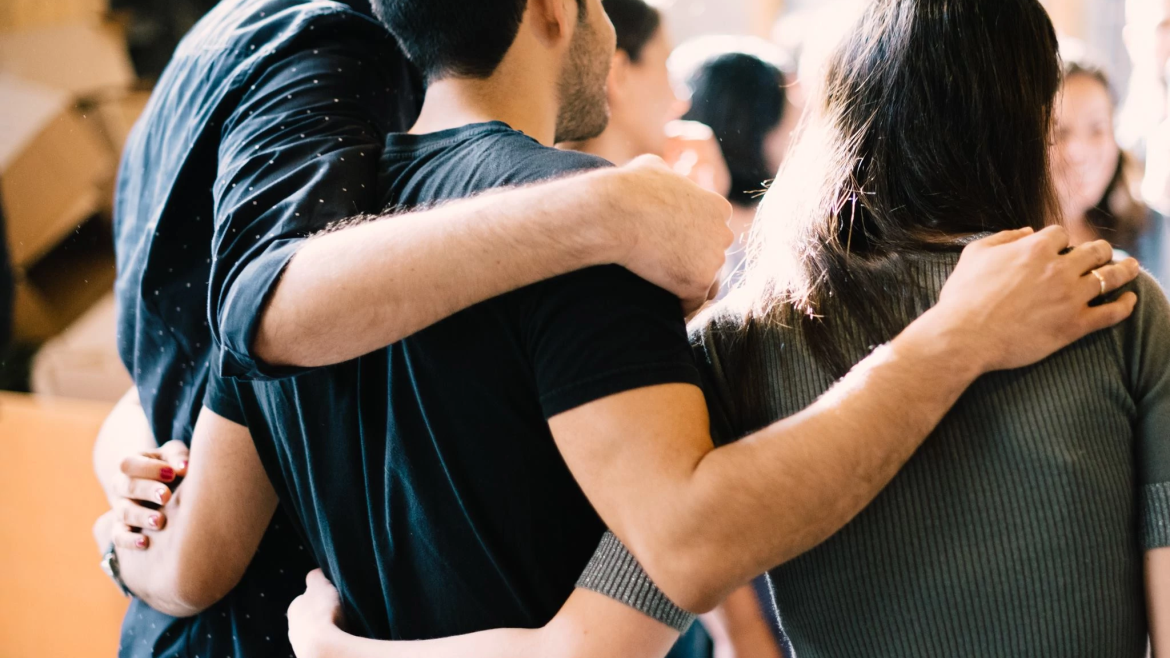 Group of young adults, linked arms.