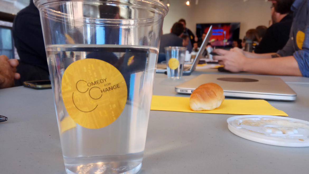 A cup on a group's table says, Comedy for Change