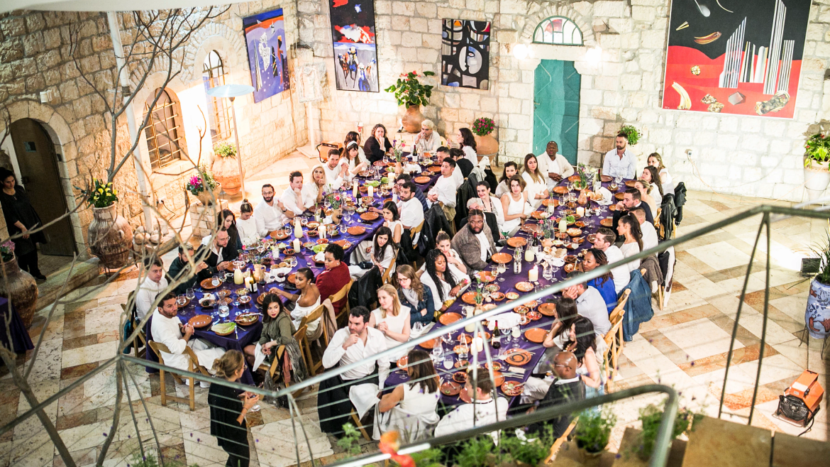 Group seated at two  tables for Shabbat dinner.