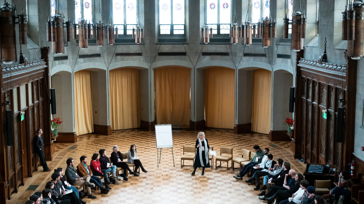 Rebecca Gruber speaking before a group sitting in a circle