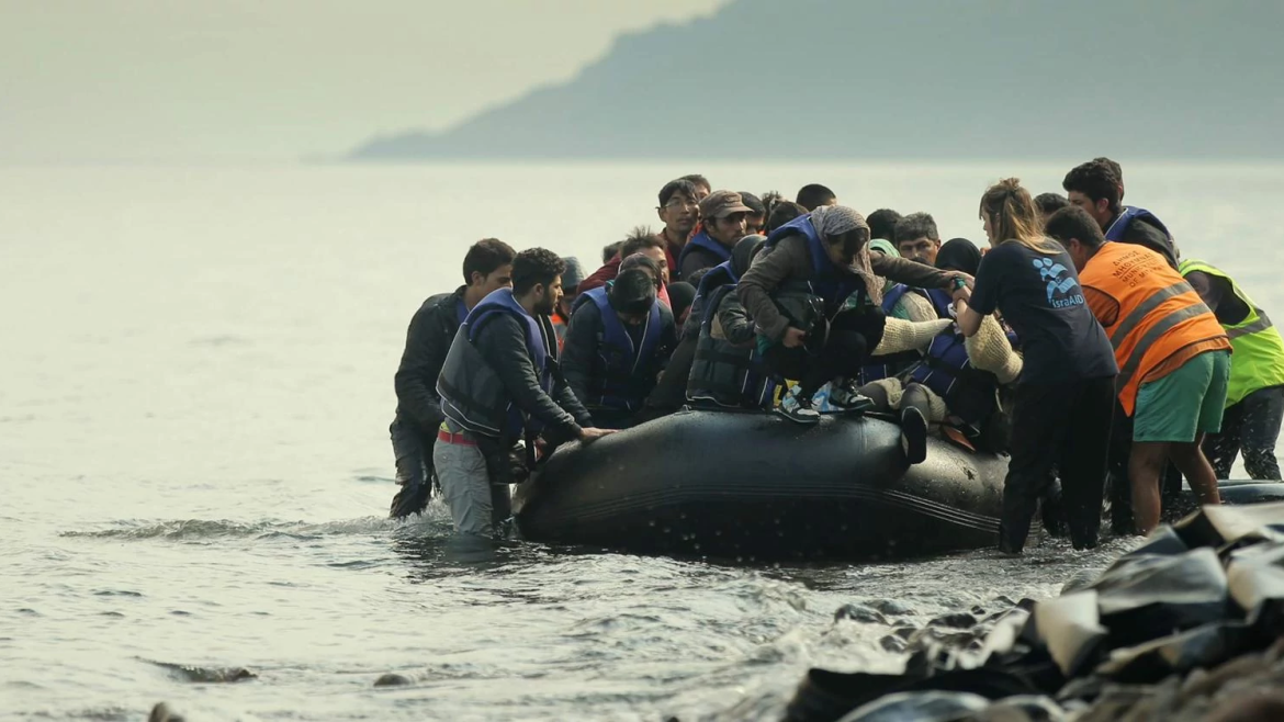 Iris Adler and her aid colleagues help refugees in a raft to pull up on a rocky beach.