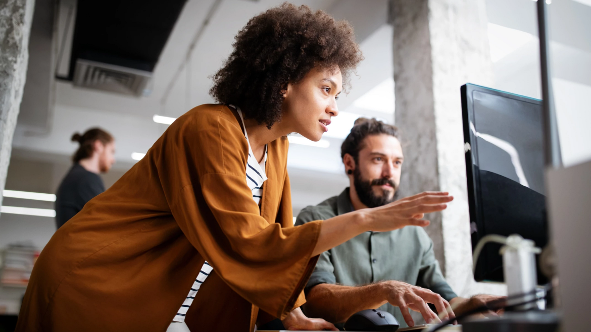 Woman advising an employee working at a computer