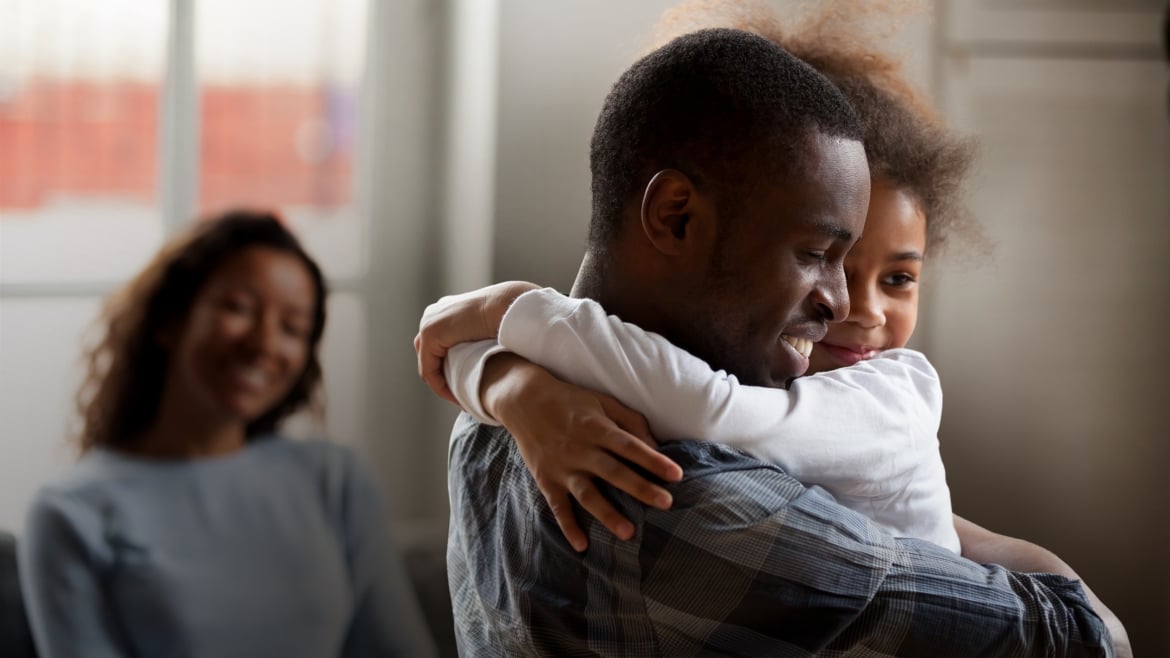 Happy man, little girl hug. A smiling woman looks on