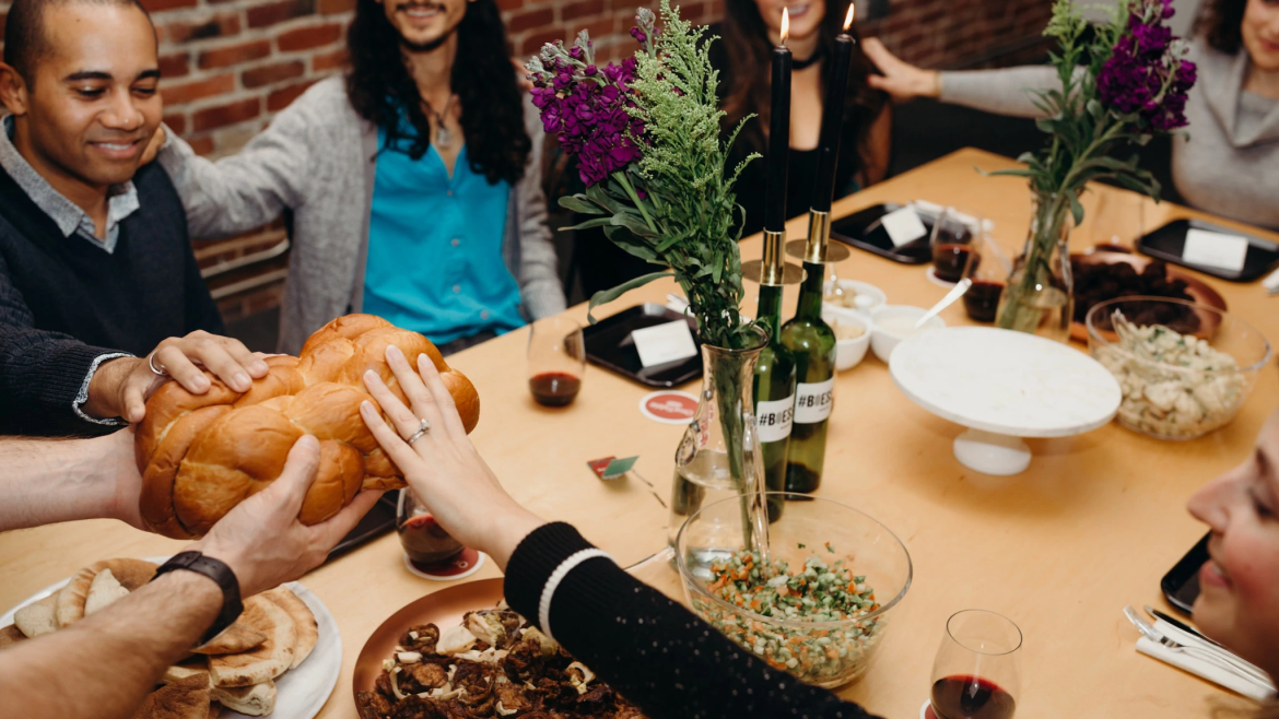 Jewish Community people dining with hands on challah