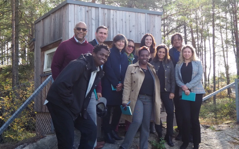 Smiling group, ten people, posing for photo on a trail in sunlight forest