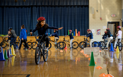 Young girl riding a bike through obstacle course in a gym